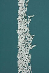 A vertical strip of white styrofoam with irregular edges on a blue background, leaving copy space