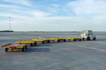 Tow tractor pulling empty luggage carts at airport