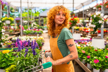 Woman pushing shopping cart choosing flowers in garden center