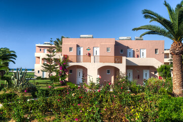 Mediterrane Hotelanlage mit Bungalows in einem parkähnlichen Resort bei schönem Sommerwetter