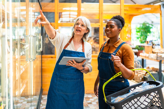 Supermarket staff managing inventory with digital tablet and basket