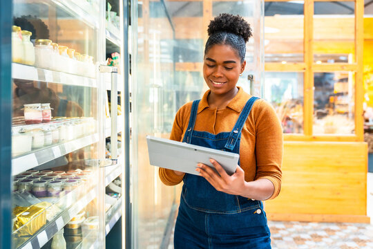 Supermarket employee using digital tablet checking inventory of dairy products