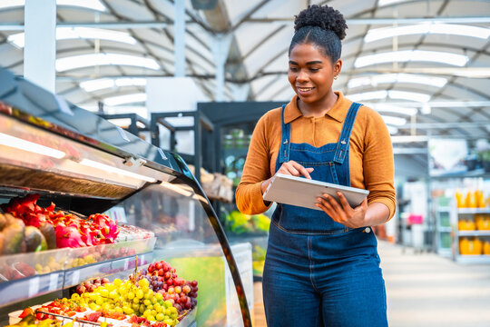 Supermarket employee using digital tablet checking products freshness