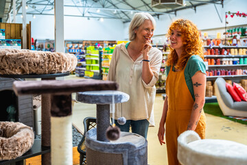 Senior woman choosing cat tree with shop assistant help