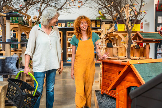 Shop assistant showing dog house to customer in pet shop