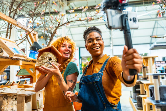 Shop assistants filming video for social media showing birdhouse