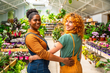 Two female florists embracing in plant nursery greenhouse