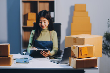 Startup SME small business entrepreneur of freelance Asian woman wearing apron using laptop and box...