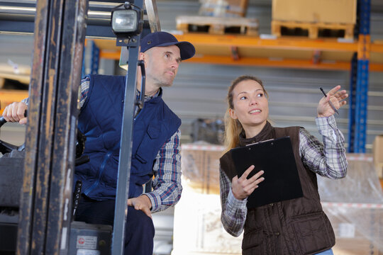 female worker and male worker in forklift at warehouse - Powered by Adobe