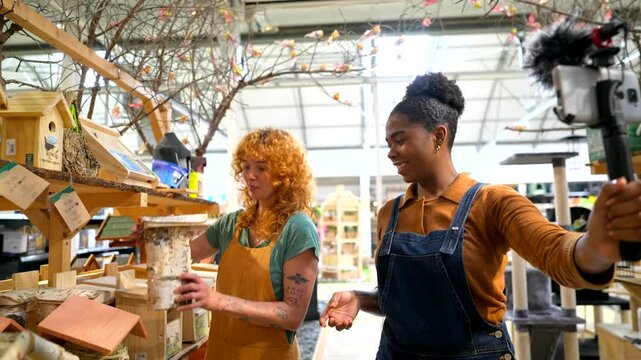 Garden center employees filming a birdhouse product review tutorial using a smartphone and gimbal