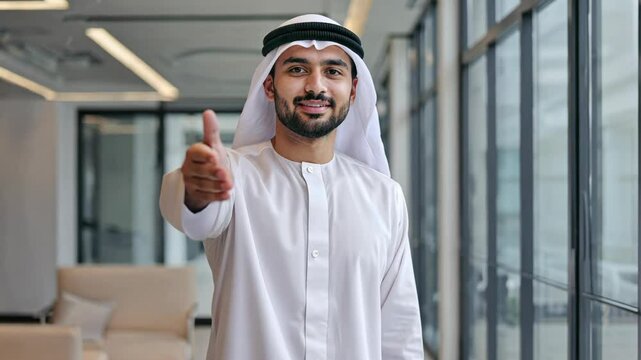 Confident man extending friendly handshake in modern glass office