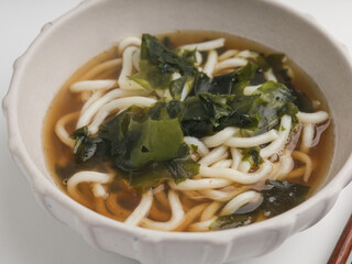 Soba noodles cooked in broth with seaweed, isolated on white background