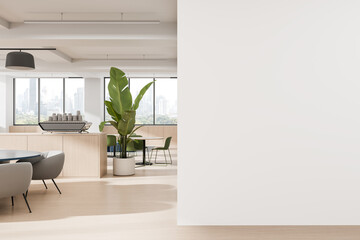 Modern office lounge interior with minimalist furniture, large windows, indoor plant, and coffee...