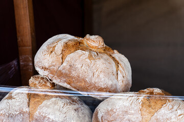 Freshly baked round artisan bread loaves stacked on a market stall, featuring crusty golden crust and light flour dusting.