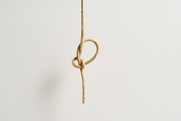 Minimalist Beige Twine Loop Knot Suspended Mid-Air Against White Background
