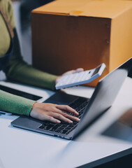Startup SME small business entrepreneur of freelance Asian woman wearing apron using laptop and box...