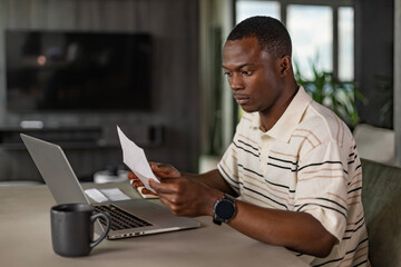 Serious african businessman concentrated reading from whom letters, received a bad news, male manager employee unpacking banking notification