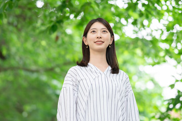 新緑の中に立つ笑顔の女性