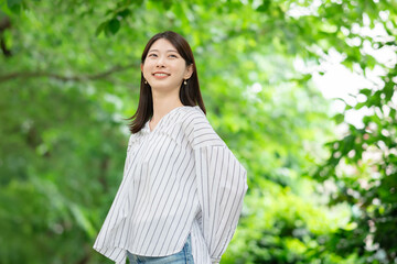 新緑の中に立つ笑顔の女性