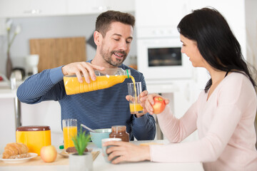 couple in love pouring orange juice at breakfast