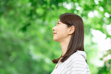 Fototapeta premium 新緑の中に立つ笑顔の女性