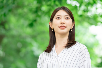新緑の中に立つ笑顔の女性
