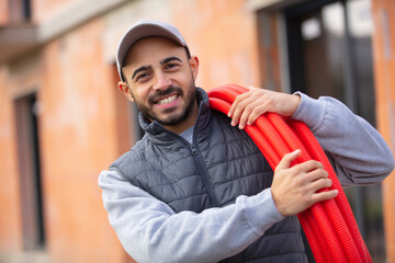 happy construction worker holding red pipes