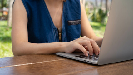 A person working on a laptop outdoors, showcasing a focused moment of productivity in a natural...