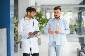 Doctor listening to patient explaining symptoms in hospital corridor