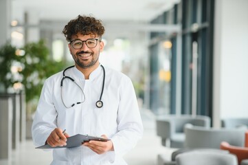 Smiling doctor writing notes on clipboard in hospital lobby