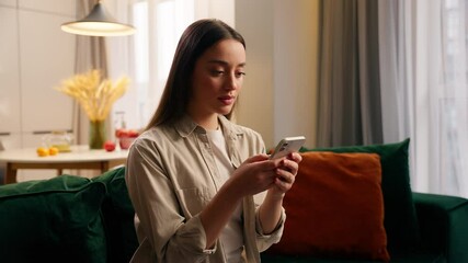 Caucasian woman using mobile phone at home concentrated girl female chatting texting smartphone chat booking service order food delivery in living room online app social media use internet shopping - Powered by Adobe