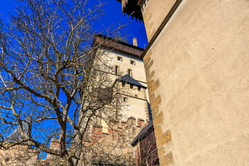 Historic stone fortress tower with leafless winter tree against clear blue sky