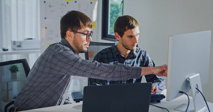 Team adult male engineer collaborate on robotic hand project using AI code solutions machine learning at tech workspace. Artificial intelligence interface, collaboration support prototype development.