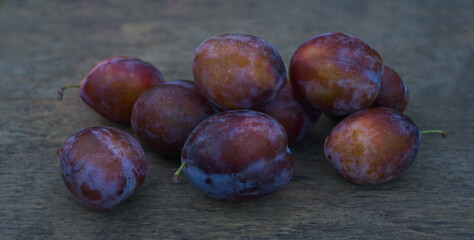 Large plums are scattered on the table.