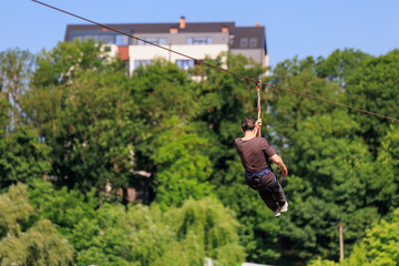 Young caucasian male enjoying zipline adventure over lush forest background