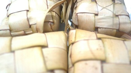 Traditional ketupat woven from young coconut leaves, commonly served during Eid al-Fitr and festive celebrations in Indonesia. Cultural food background.