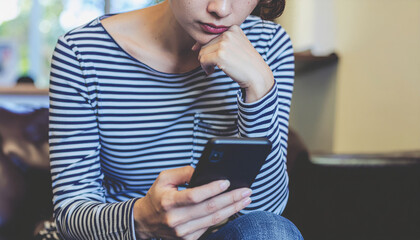 A woman is seeing stock market; thinking while trading on the mobile phone