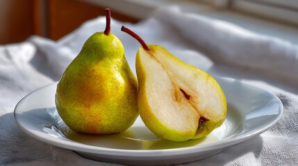 Whole and Halved Pear on a White Plate