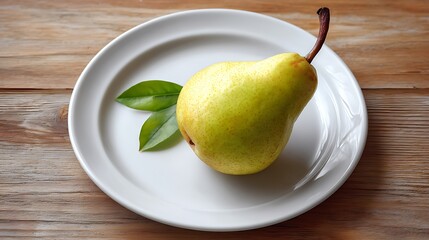 Ripe pear with leaves placed on a white plate over a wooden surface