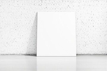 Blank white canvas leaning against a white brick wall in a minimalist space.