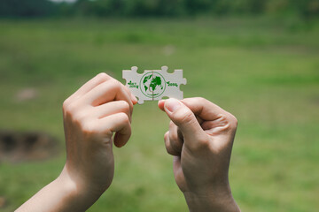 Hands Holding Eco-Friendly Puzzle Piece with Earth Design Outdoors