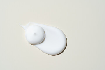 White cosmetic cream texture, skincare lotion swatch on light beige background. Face creme, body moisturizer, hair conditioner smear smudge stroke. Creamy beauty product closeup