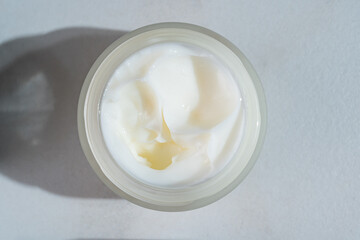 close up of collagen cream in open glass jar on marble background. Presentation of skin care beauty products. Swirl of cream, promotion product showcase