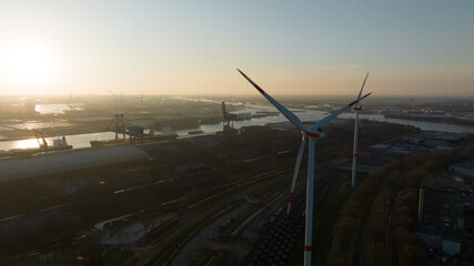 wind turbine in the port of Amsterdam, showcasing heavy industry, transport over water and renewable energy. Aerial photo at sunset.