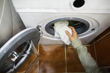 Person Loading Laundry into Front-Loading Washing Machine in Home Laundry Room