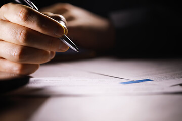 Close-up of Hand Writing with Pen on Paper Document in Low Light
