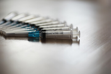 Close-up of Medical Syringes with Needles Aligned on a Reflective Surface in a Healthcare Setting
