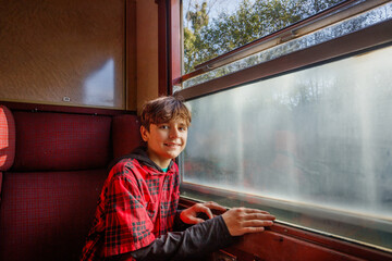 Boy teenager smiles inside carriage sitting near the window
