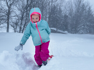 Child in bright winter gear enjoying a snowy outdoor adventure