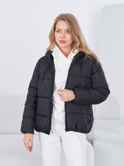 Fashionable woman poses in stylish black jacket inside modern studio